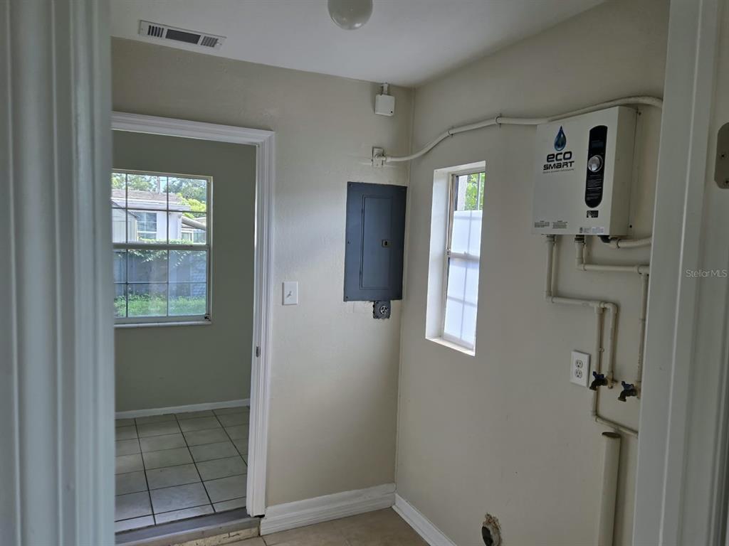 A laundry room features an electrical panel, a tankless water heater, and a doorway to another room — 5772 94TH AVENUE N, PINELLAS PARK, FL