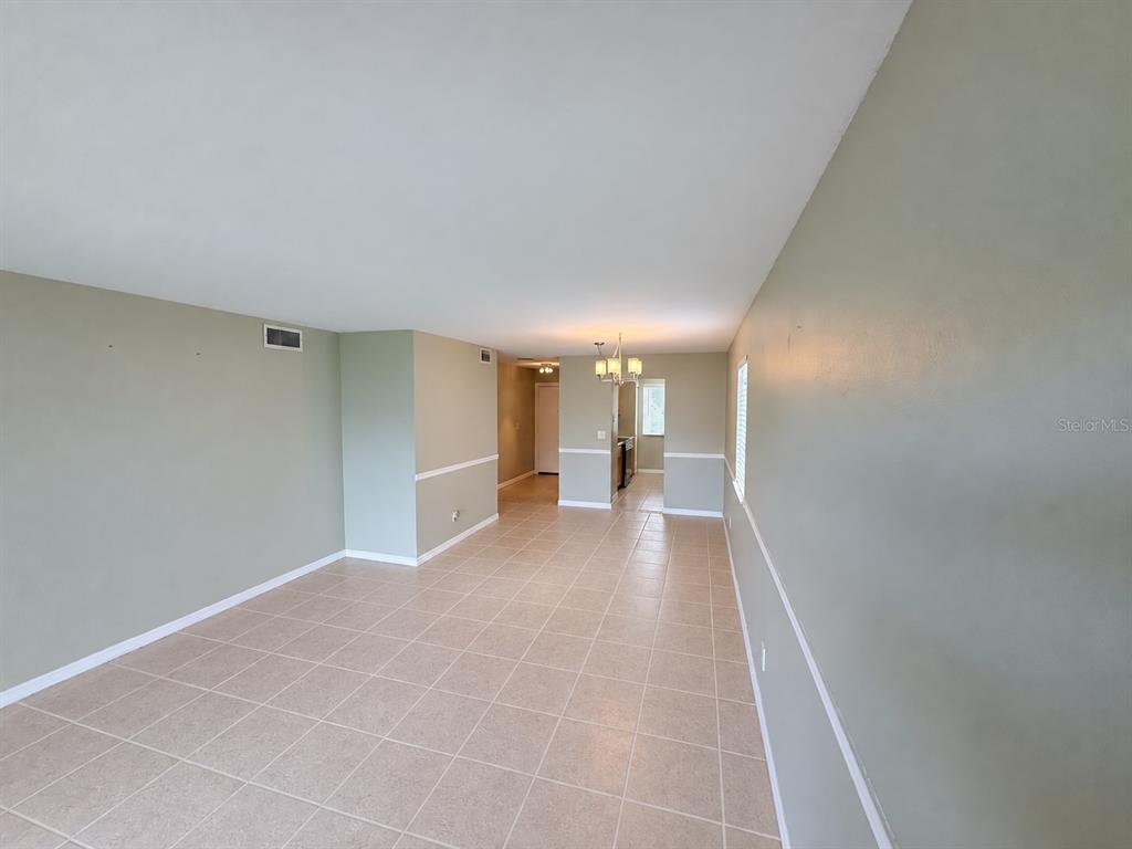An open-concept room features light-colored tile flooring, sage green walls with white wainscoting, and a chandelier — 6519 W NEWBERRY ROAD UNIT 305, GAINESVILLE, FL