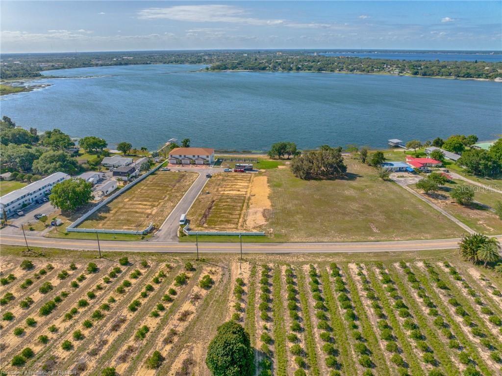 An aerial view shows a large lakefront property with vacant lots and a citrus grove — 1900 OASIS BOULEVARD, SEBRING, FL