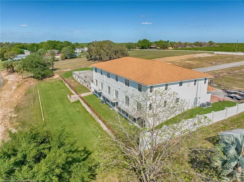 An aerial view shows a multi-story white building with a tan tile roof and balconies — 1900 OASIS BOULEVARD, SEBRING, FL