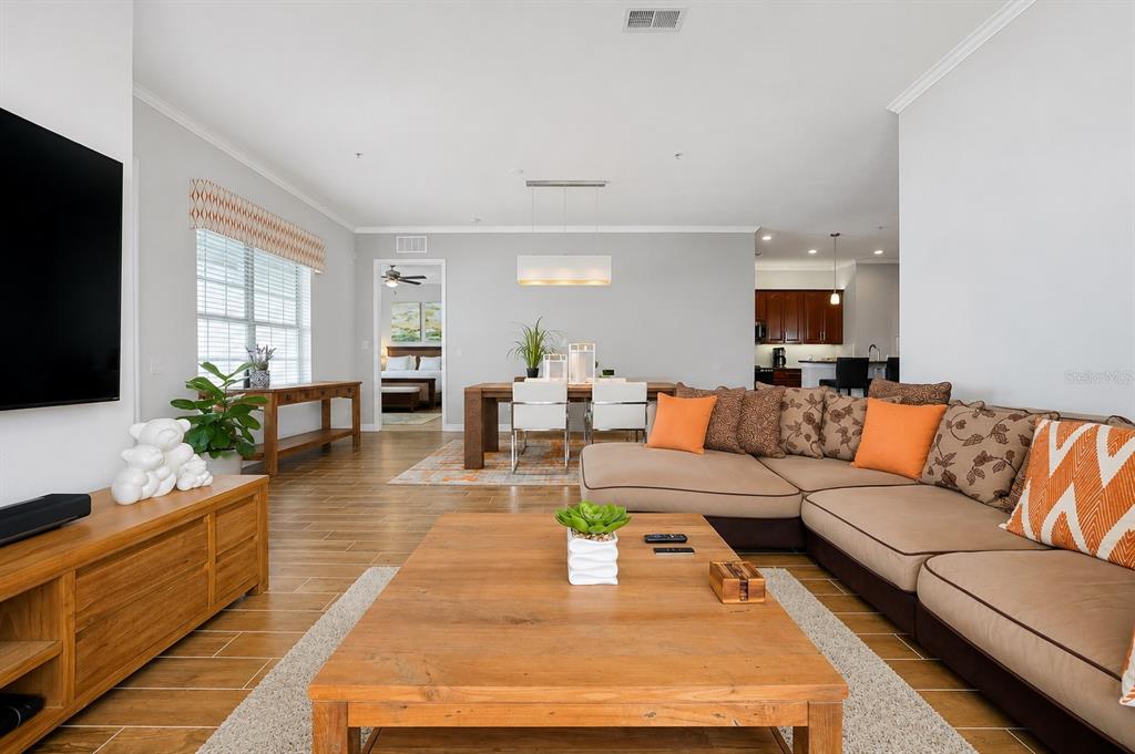 A living room with a sectional sofa, wooden coffee table, and an adjacent dining area — 5048 SHOREWAY LOOP UNIT 40404, ORLANDO, FL