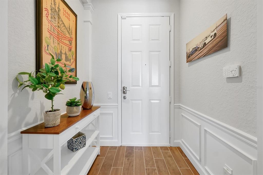 An entryway features a white door, wood-look tile floors, wainscoting, and a console table — 5048 SHOREWAY LOOP UNIT 40404, ORLANDO, FL