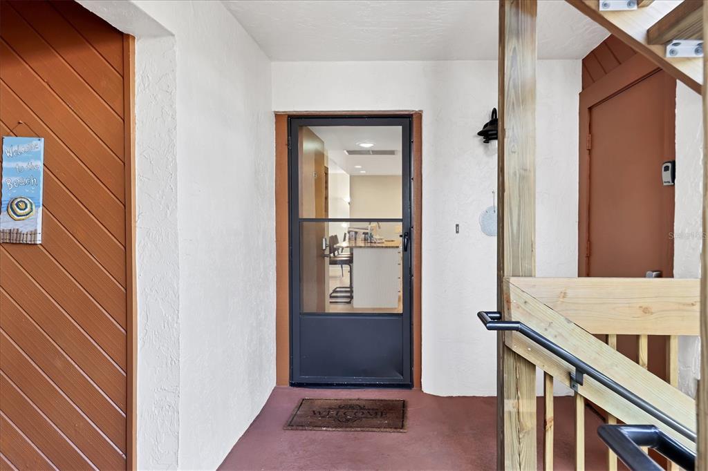 A covered entryway features a screen door, a welcome mat, and wooden stairs — 1900 COVE II PLACE UNIT 127, SARASOTA, FL