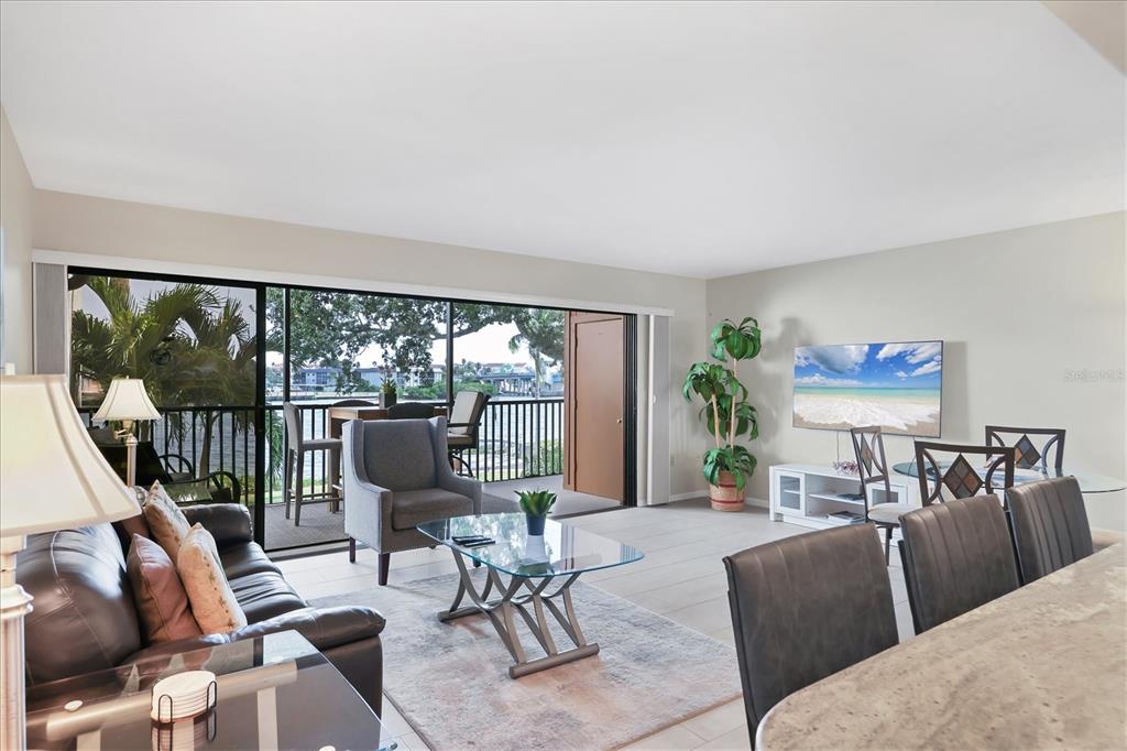 A living room with a glass coffee table, leather sofa, and sliding doors opening to a balcony — 1900 COVE II PLACE UNIT 127, SARASOTA, FL