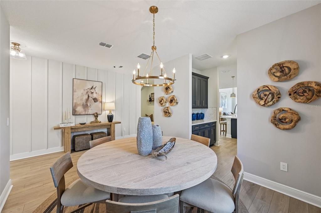 A dining room features a round wooden table, four chairs, and wall-mounted wood decor — 5977 FRESH FLORA DRIVE, WIMAUMA, FL