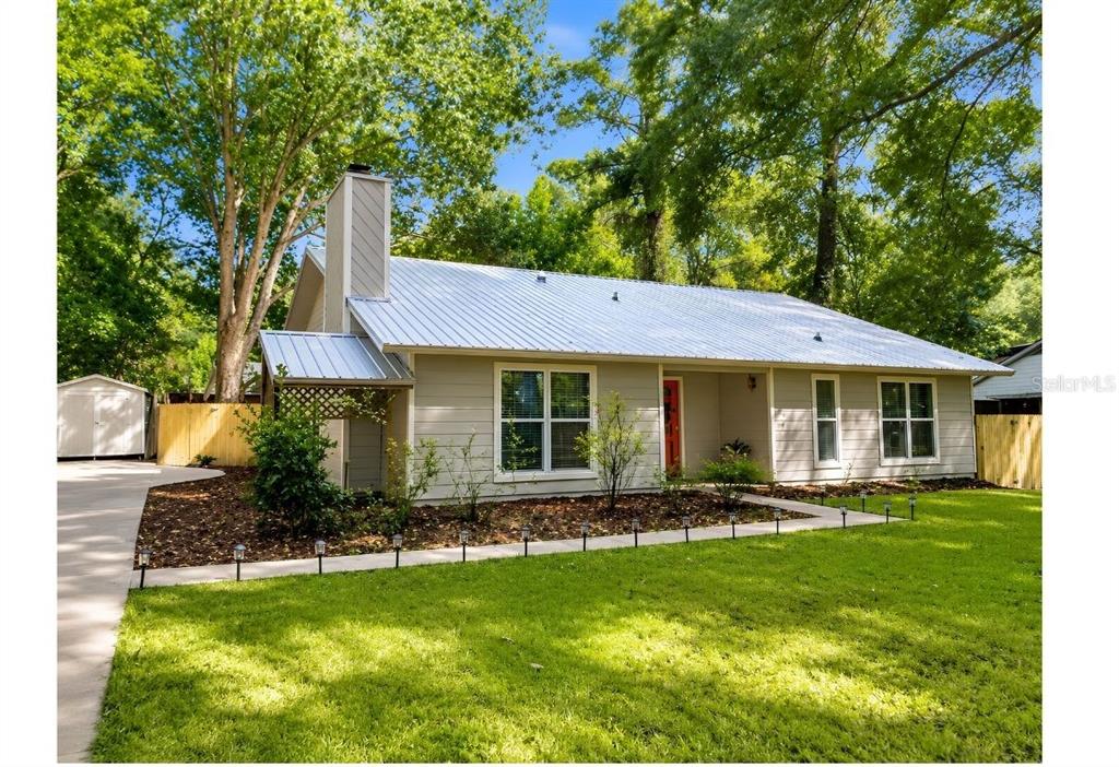 A single-story house with a metal roof, light siding, and a red front door — 731 NW 37TH STREET, GAINESVILLE, FL