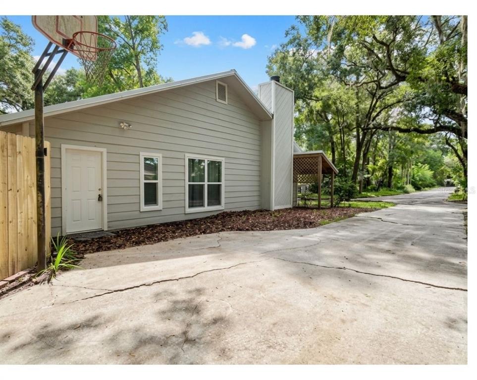 A side view of a light gray house with a concrete driveway and basketball hoop — 731 NW 37TH STREET, GAINESVILLE, FL