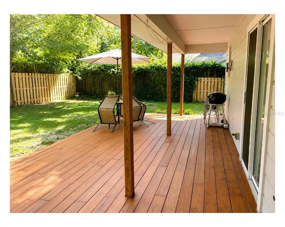 A wooden deck with a patio set and grill sits under a covered porch area — 731 NW 37TH STREET, GAINESVILLE, FL