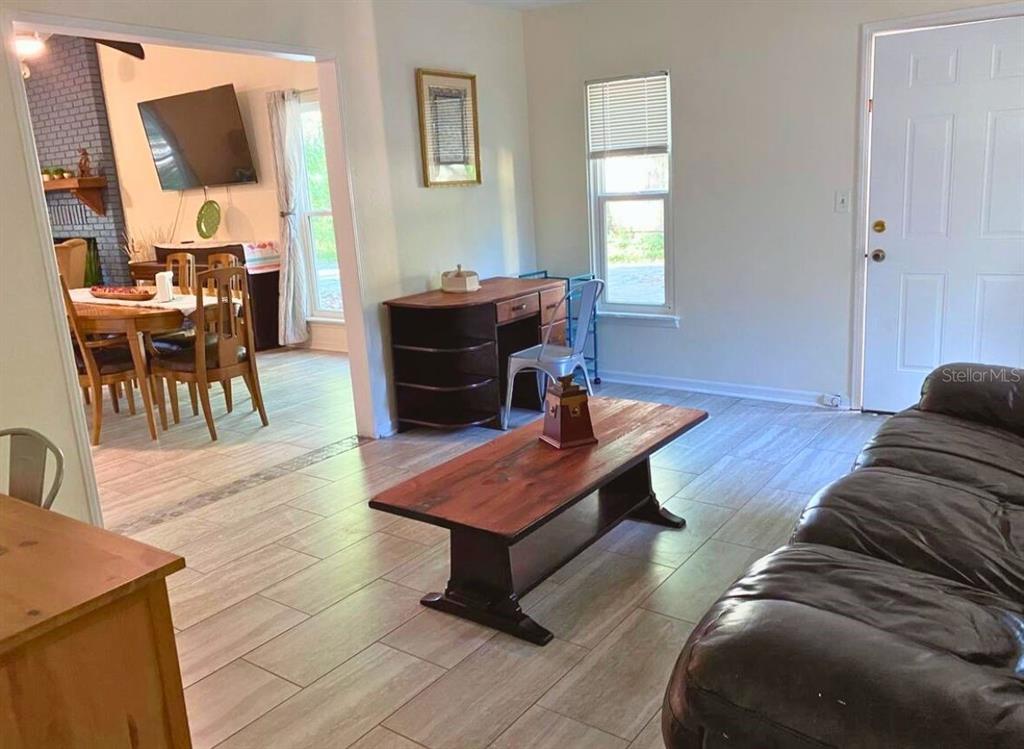 A living room with tile flooring, a coffee table, a desk, and an adjacent dining area — 731 NW 37TH STREET, GAINESVILLE, FL