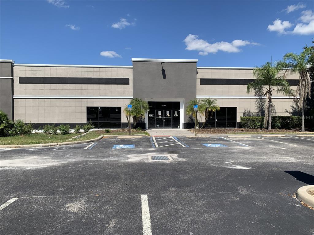 A single-story commercial building with a gray facade and a central glass entrance door — 1510 E COLLEGE AVENUE, RUSKIN, FL