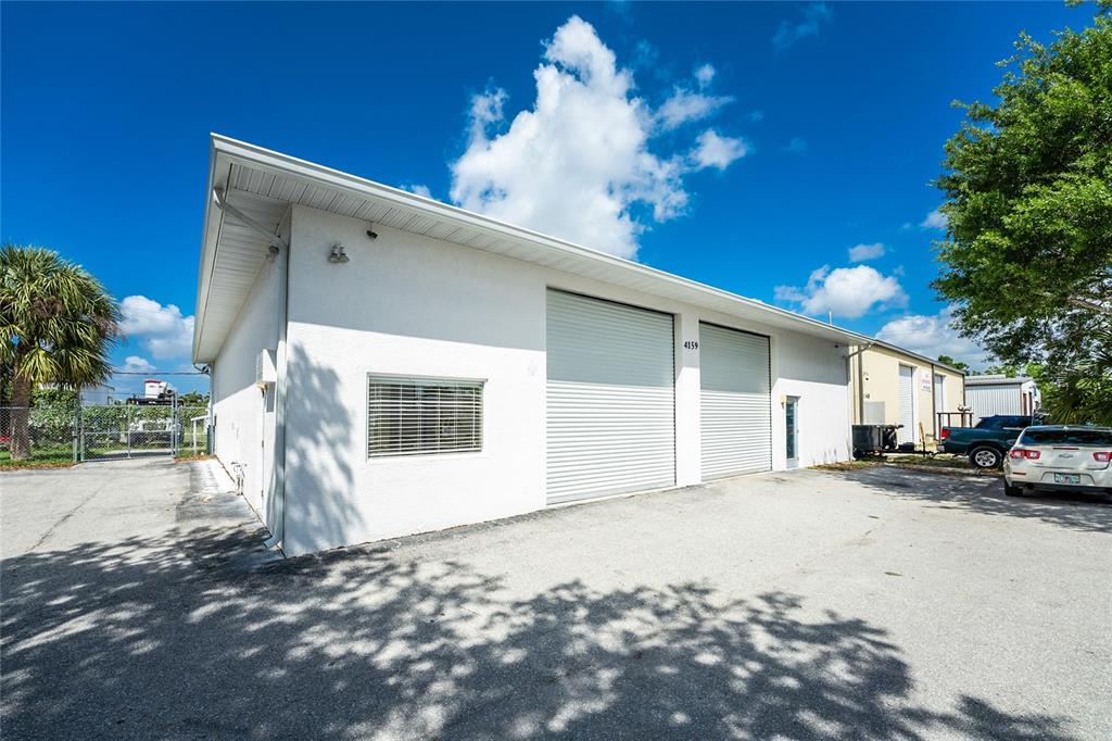 A white commercial building with two roll-up garage doors and a window on a paved lot — 4159 ELECTRIC WAY, PUNTA GORDA, FL