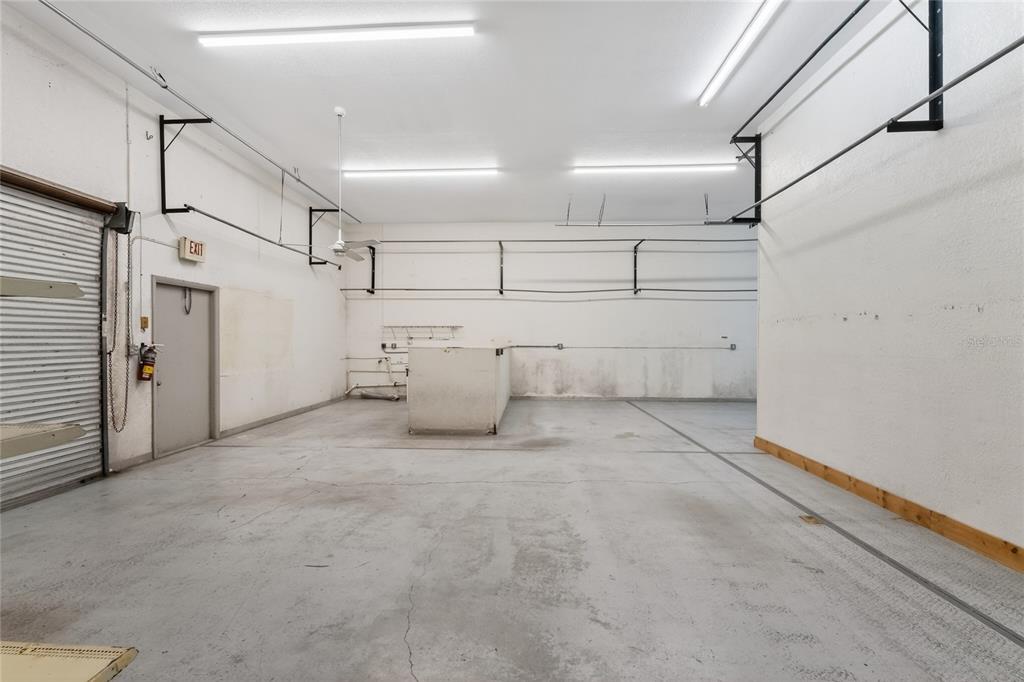 An empty garage with concrete floors, white walls, exposed ceiling lights, and a side door — 4159 ELECTRIC WAY, PUNTA GORDA, FL
