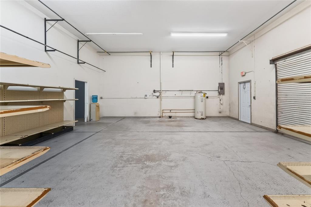 An empty commercial storage room features concrete floors, metal shelving units, and a water heater — 4159 ELECTRIC WAY, PUNTA GORDA, FL