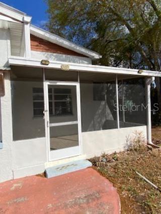 A white screened-in porch with a door sits on a concrete patio beside a house — 312 MILAKEE AVENUE, SEBRING, FL
