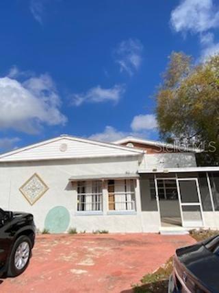 A single-story house with a white stucco exterior, a screened porch, and a red driveway — 312 MILAKEE AVENUE, SEBRING, FL