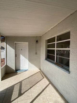 A covered patio with tiled flooring, a white door, and a horizontal sliding window — 312 MILAKEE AVENUE, SEBRING, FL