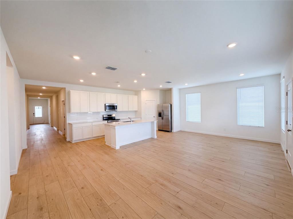 An open-concept kitchen and living area features white cabinetry, a central island, and wood flooring — 347 PUMA LOOP, GROVELAND, FL