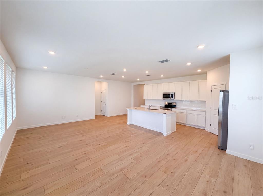 A bright, open-concept kitchen features white cabinetry, a central island, and light wood flooring — 347 PUMA LOOP, GROVELAND, FL