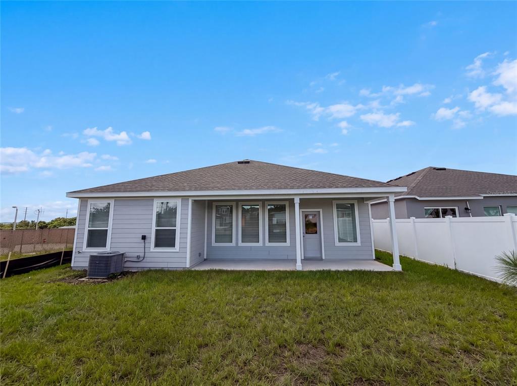 The exterior rear view of a single-story house features light gray siding and a patio — 347 PUMA LOOP, GROVELAND, FL