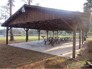 A large, open-air wooden pavilion with picnic tables sits on a concrete slab near trees — 7TH LOOP, SILVER SPRINGS, FL