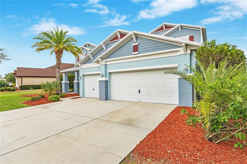 A blue two-story house features a three-car garage and palm trees in the front yard — 5331 SANDY SHELL DRIVE, APOLLO BEACH, FL