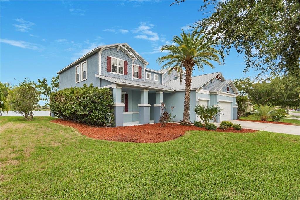 A two-story blue house with a palm tree and a front porch sits on grass — 5331 SANDY SHELL DRIVE, APOLLO BEACH, FL