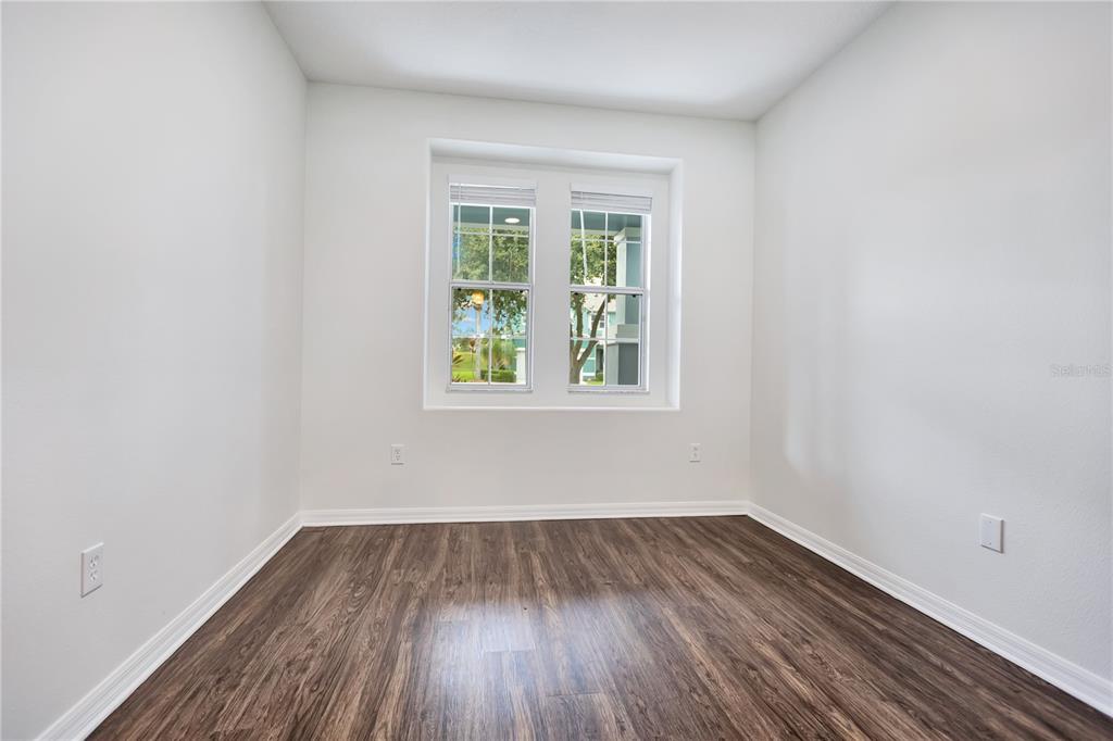An empty room with white walls, dark wood-look flooring, and a double window — 5331 SANDY SHELL DRIVE, APOLLO BEACH, FL
