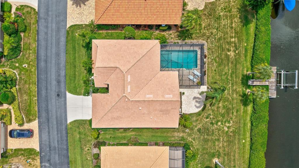 An aerial view shows a house with a tiled roof, a screened pool, and a dock — 103 INLETS BOULEVARD UNIT 103, NOKOMIS, FL