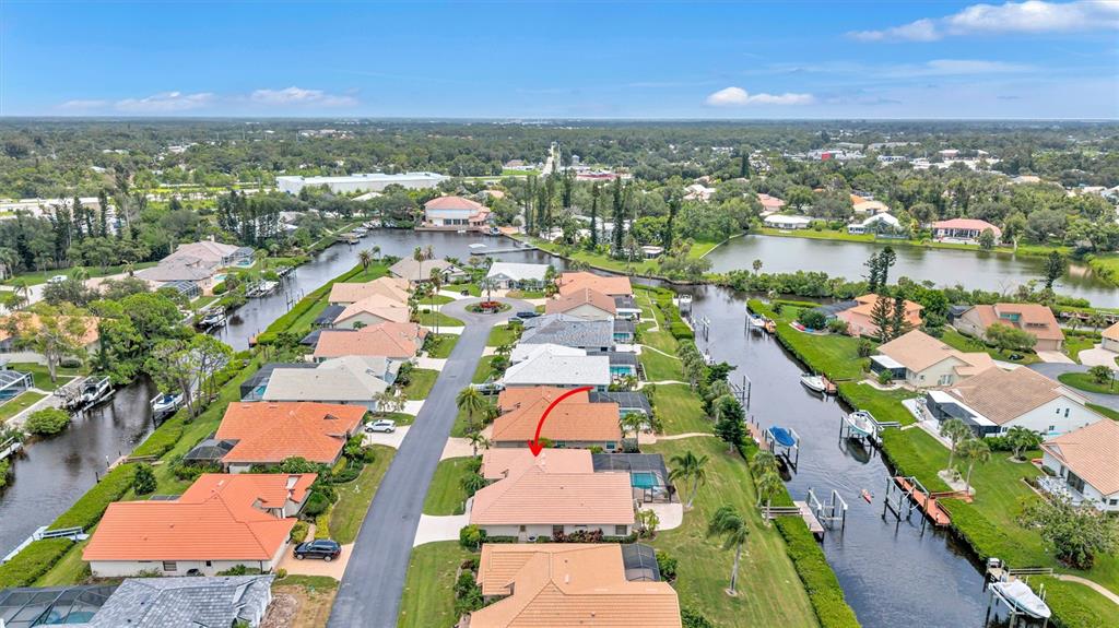 An aerial view shows a residential neighborhood with houses along canals and a red arrow — 103 INLETS BOULEVARD UNIT 103, NOKOMIS, FL