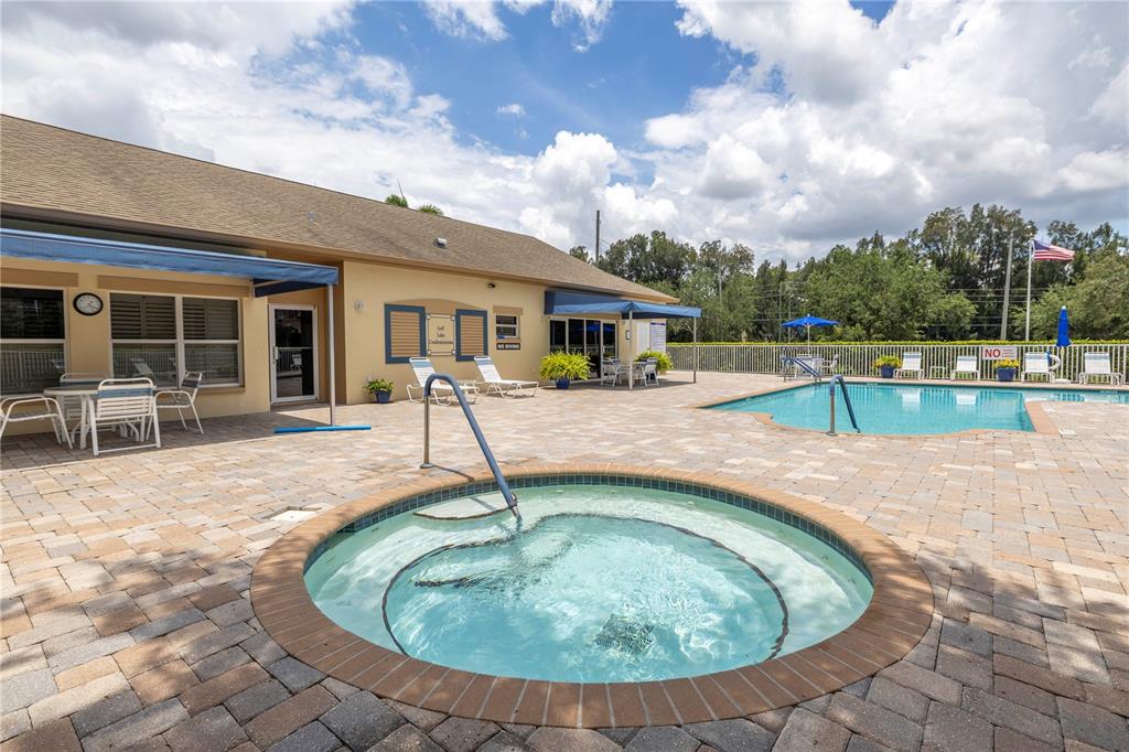 A round hot tub sits on a paved pool deck next to a swimming pool — 960 STARKEY ROAD UNIT 2202, LARGO, FL