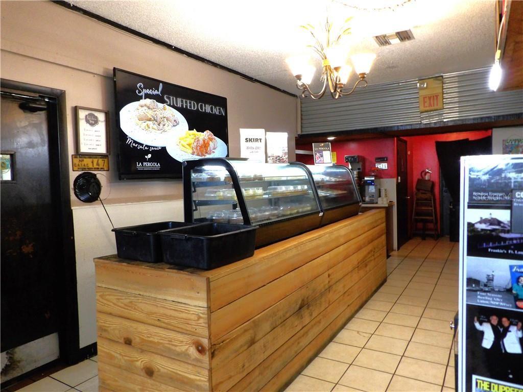 A commercial space features a wooden service counter, a glass display case, and menu signage — 2780 N FLORIDA AVENUE, HERNANDO, FL