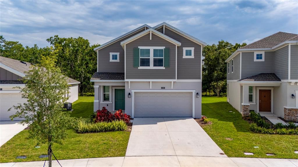 A two-story suburban house with a gray exterior, a two-car garage, and a green front door — 4385 TWISTED TWIG BEND, KISSIMMEE, FL