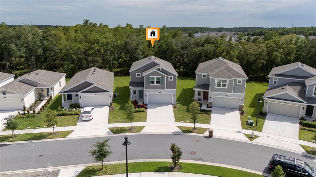 An aerial view shows a row of suburban houses with driveways facing a curved street — 4385 TWISTED TWIG BEND, KISSIMMEE, FL