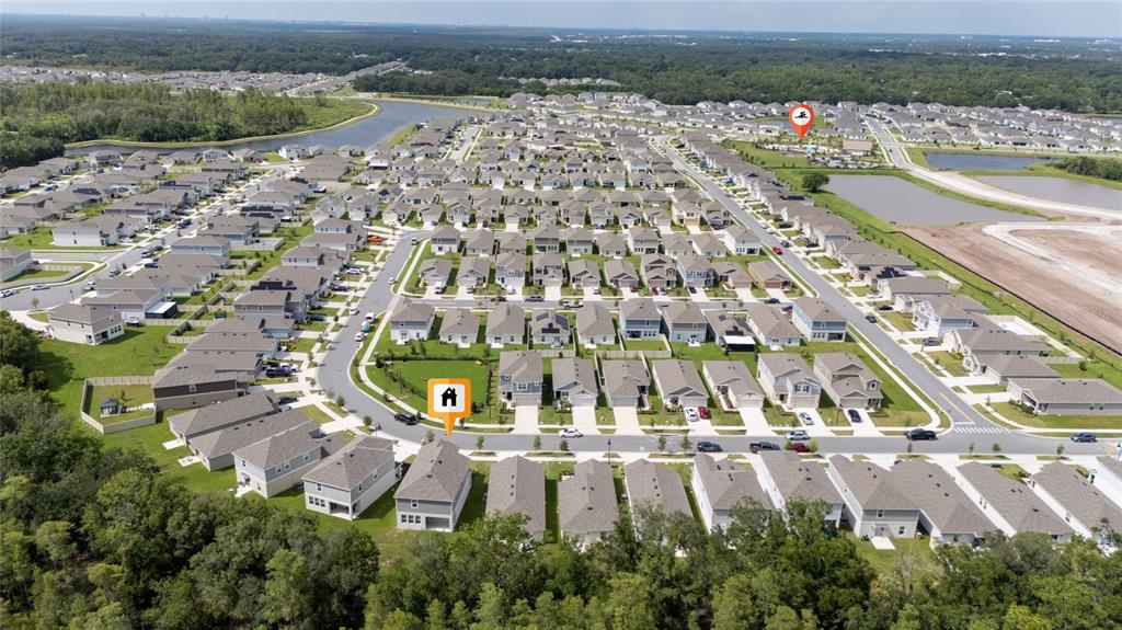 An aerial view shows a suburban neighborhood with many single-family homes and a community pool — 4385 TWISTED TWIG BEND, KISSIMMEE, FL