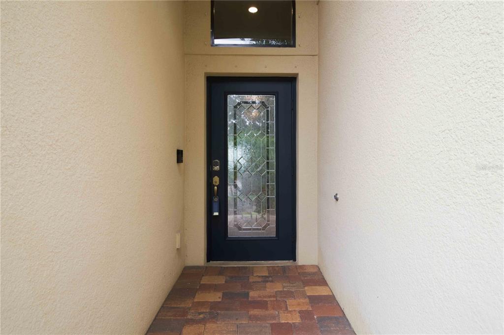 A dark front door with a glass insert sits at the end of a walkway — 13422 SAW PALM CREEK TRAIL, LAKEWOOD RANCH, FL