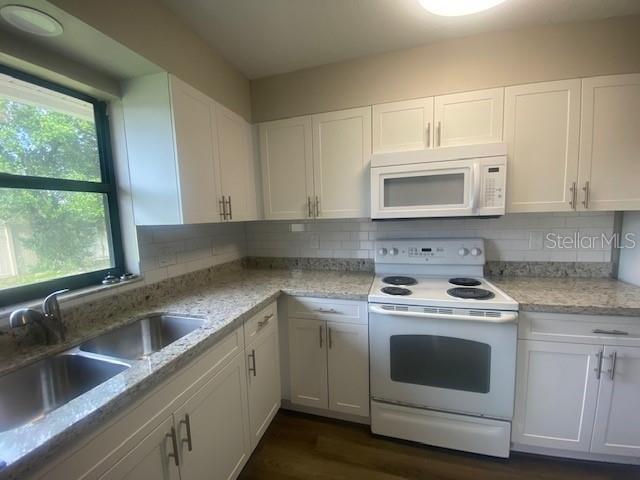 A kitchen with white cabinets, granite countertops, a double sink, and white appliances — 3622 WILLOW OAK ROAD, MULBERRY, FL