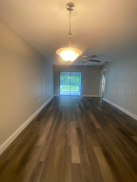 An empty room features wood-look flooring, a hanging light fixture, and a sliding glass door — 3622 WILLOW OAK ROAD, MULBERRY, FL