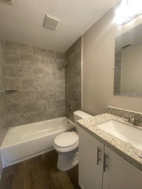 A bathroom features a tub with gray tile walls, a white toilet, and a granite vanity — 3622 WILLOW OAK ROAD, MULBERRY, FL