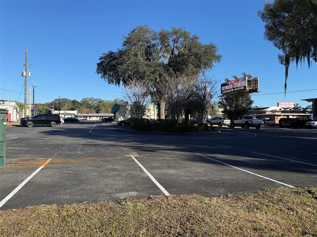 A large, paved parking lot features a central tree island and a prominent billboard — 1536 S PINE AVENUE, OCALA, FL
