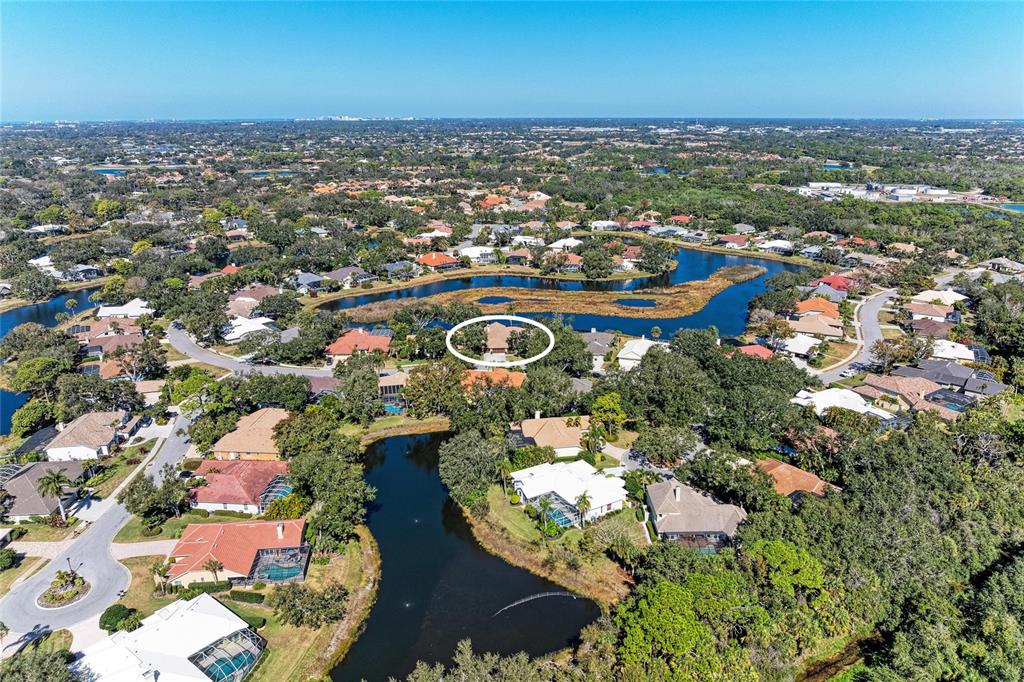 An aerial view shows a residential neighborhood with houses surrounding a winding lake — 8383 CYPRESS HOLLOW DRIVE, SARASOTA, FL