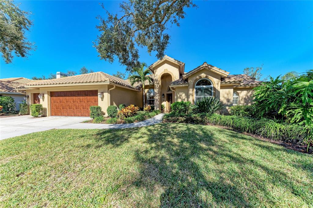 A single-story tan stucco house with a tile roof and a two-car garage — 8383 CYPRESS HOLLOW DRIVE, SARASOTA, FL