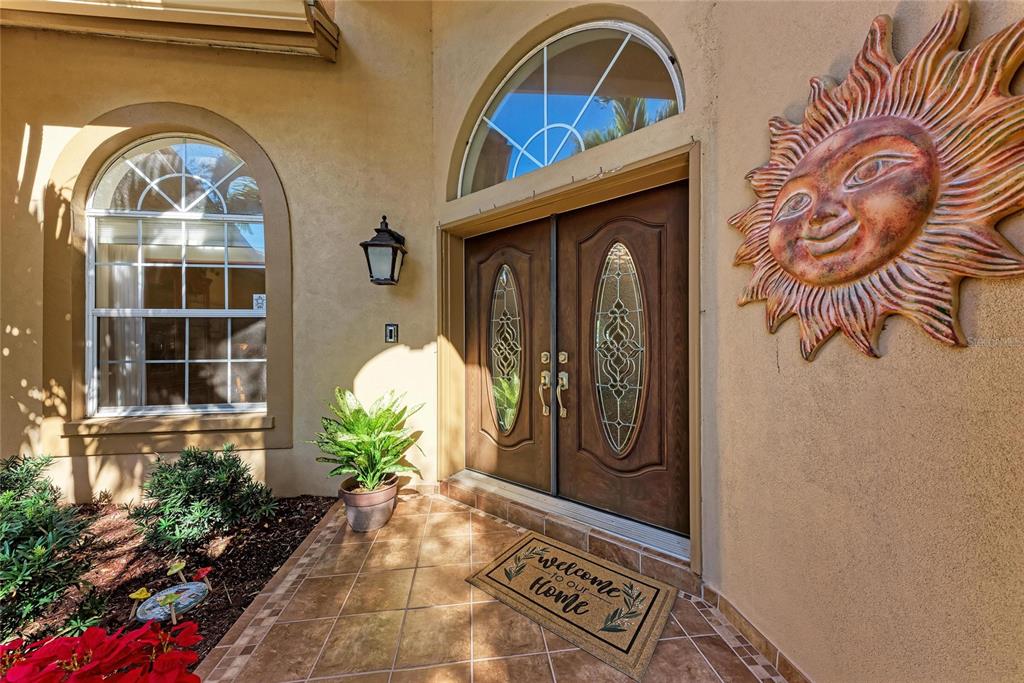 A front entryway features double wood doors, a sun wall decoration, and a welcome mat — 8383 CYPRESS HOLLOW DRIVE, SARASOTA, FL