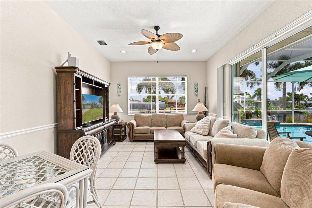 A screened-in patio features a swimming pool, outdoor dining furniture, and a view of water — 136 PECKHAM STREET SE, PORT CHARLOTTE, FL