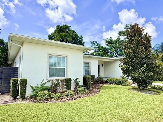 A single-story house with white stucco walls, a shingled roof, and a manicured front lawn — 2408 CORRINE DRIVE, ORLANDO, FL
