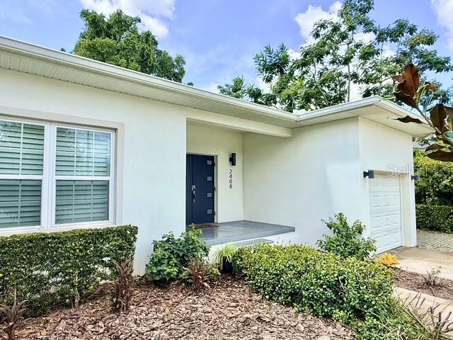 A white single-story house features a dark blue front door and a small attached garage — 2408 CORRINE DRIVE, ORLANDO, FL