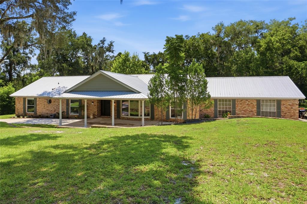 A single-story brick house with a metal roof and a covered front porch — 1150 MARKHAM WOODS ROAD, LONGWOOD, FL