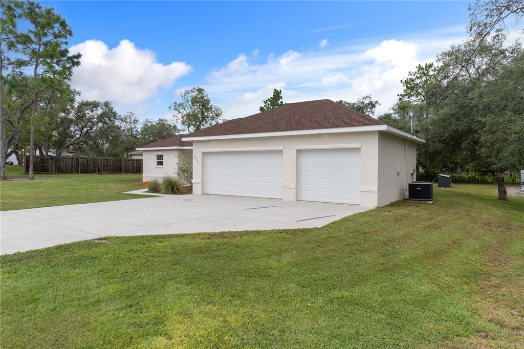 A detached two-car garage with a concrete driveway sits on a grassy lot — 8451 NUZUM ROAD, WEEKI WACHEE, FL