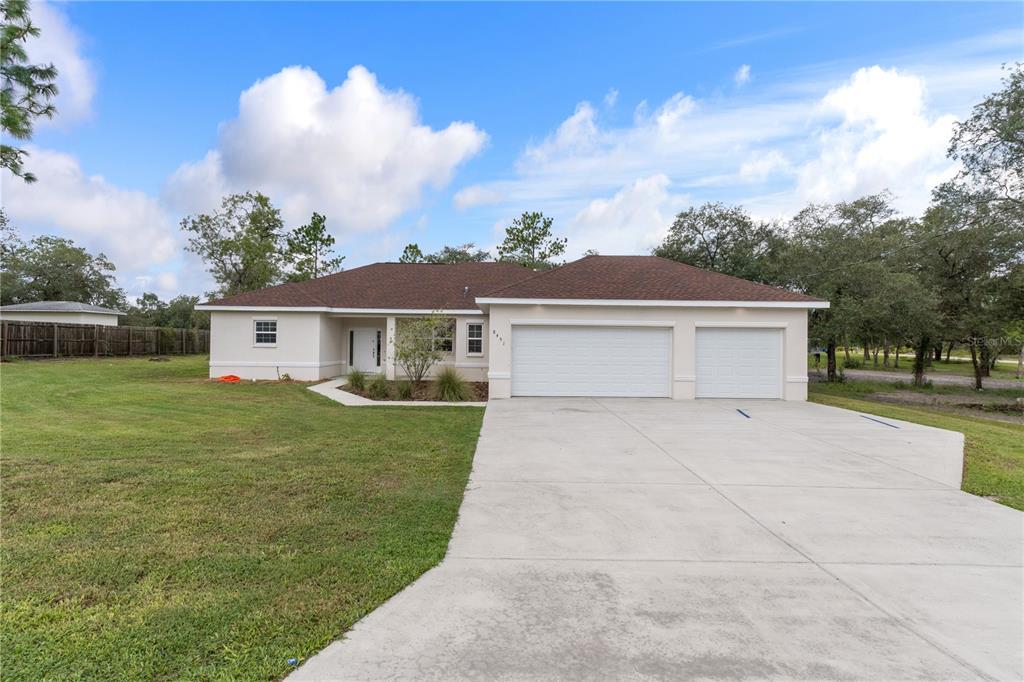 A single-story house with a brown roof, beige stucco exterior, and a three-car garage — 8451 NUZUM ROAD, WEEKI WACHEE, FL