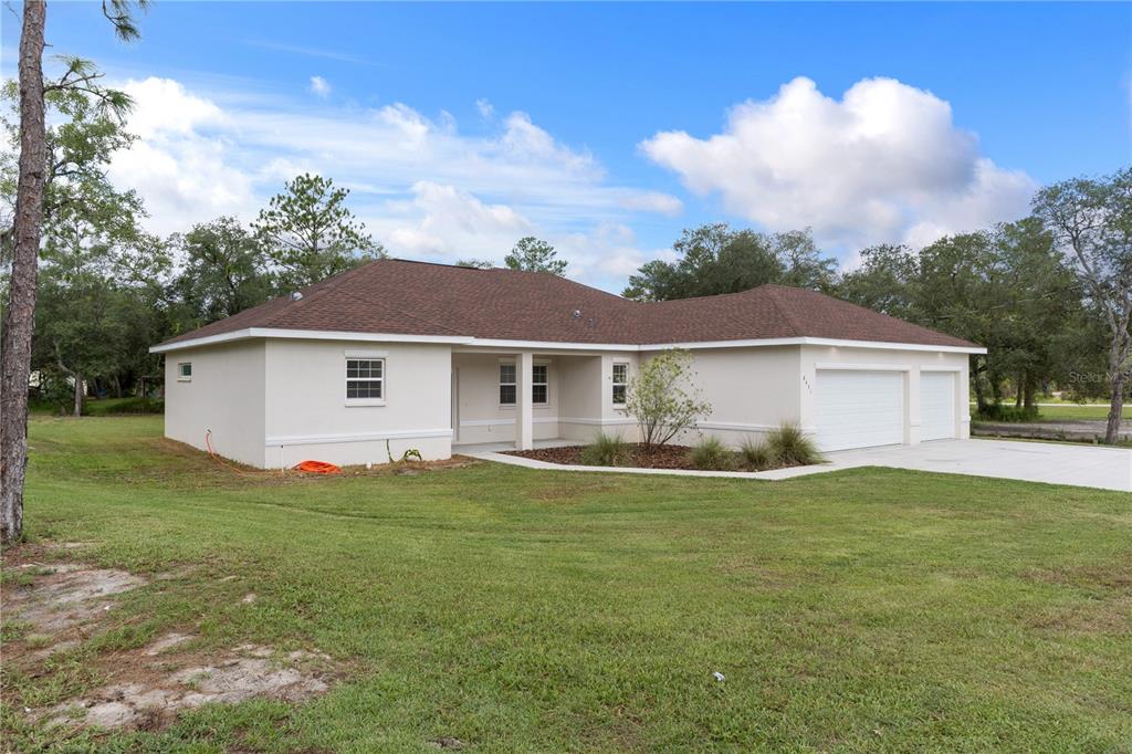 A single-story house with a beige stucco exterior, brown roof, and a two-car garage — 8451 NUZUM ROAD, WEEKI WACHEE, FL
