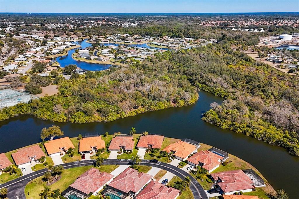 An aerial view shows a residential neighborhood with tile-roofed houses bordering a winding waterway — E SKLAR DRIVE, VENICE, FL